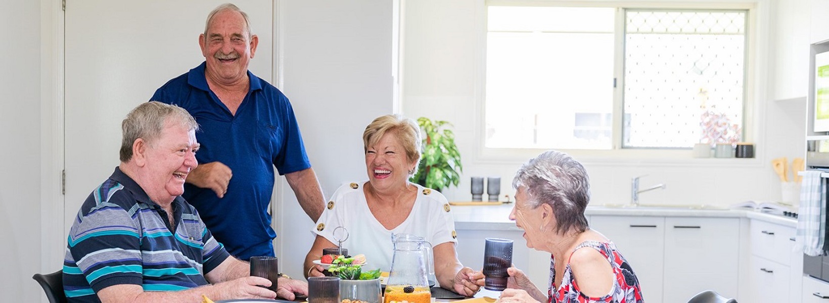 A group of seniors sitting around the coffee table laughing A group of seniors sitting around the coffee table laughing