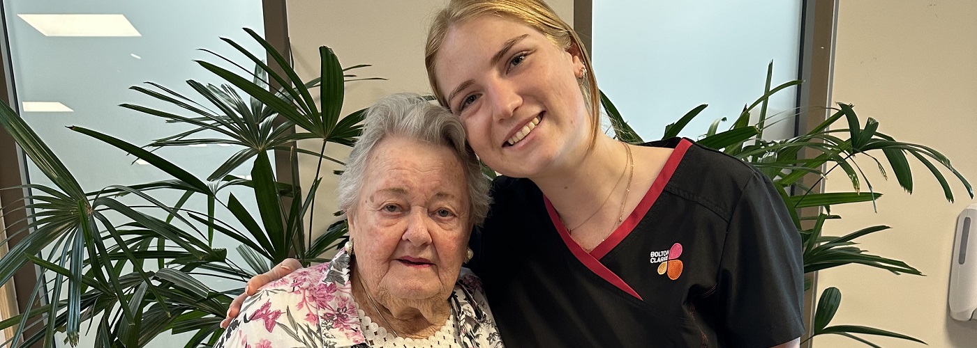 An elderly resident and young carer, smiling