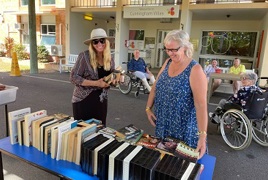 Two ladies smiling while shopping for secondhand books Two ladies smiling while shopping for secondhand books